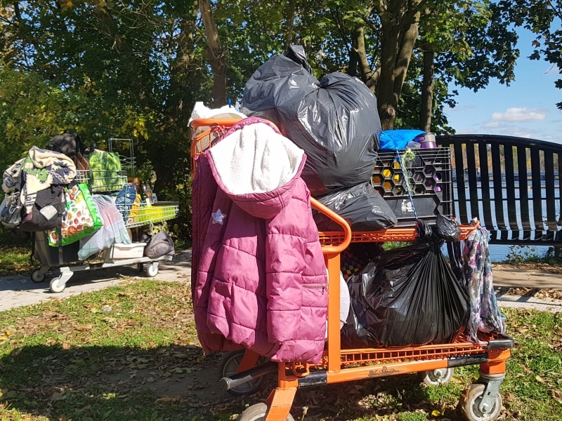 Two shopping carts loaded with clothes and bags.
