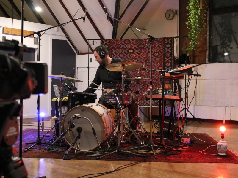 Bennett Bedoukian plays a drumset, indoors.