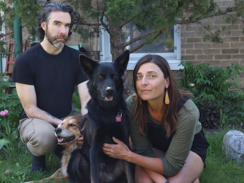 Photo shows Emily Minthorn and her husband Chris Lawson sitting on the front lawn of their East City apartment with their two dogs.