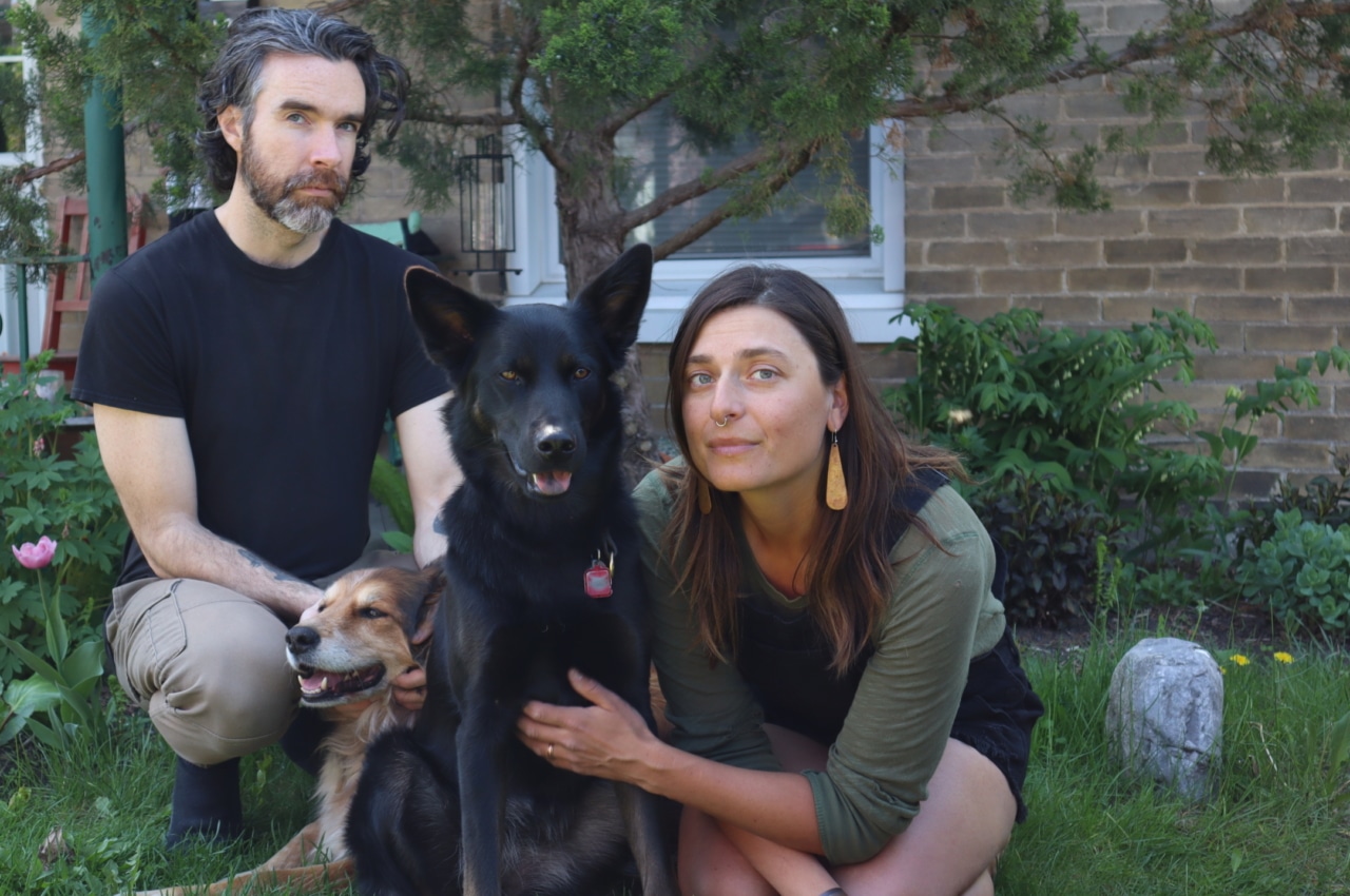 Photo shows Emily Minthorn and her husband Chris Lawson sitting on the front lawn of their East City apartment with their two dogs.