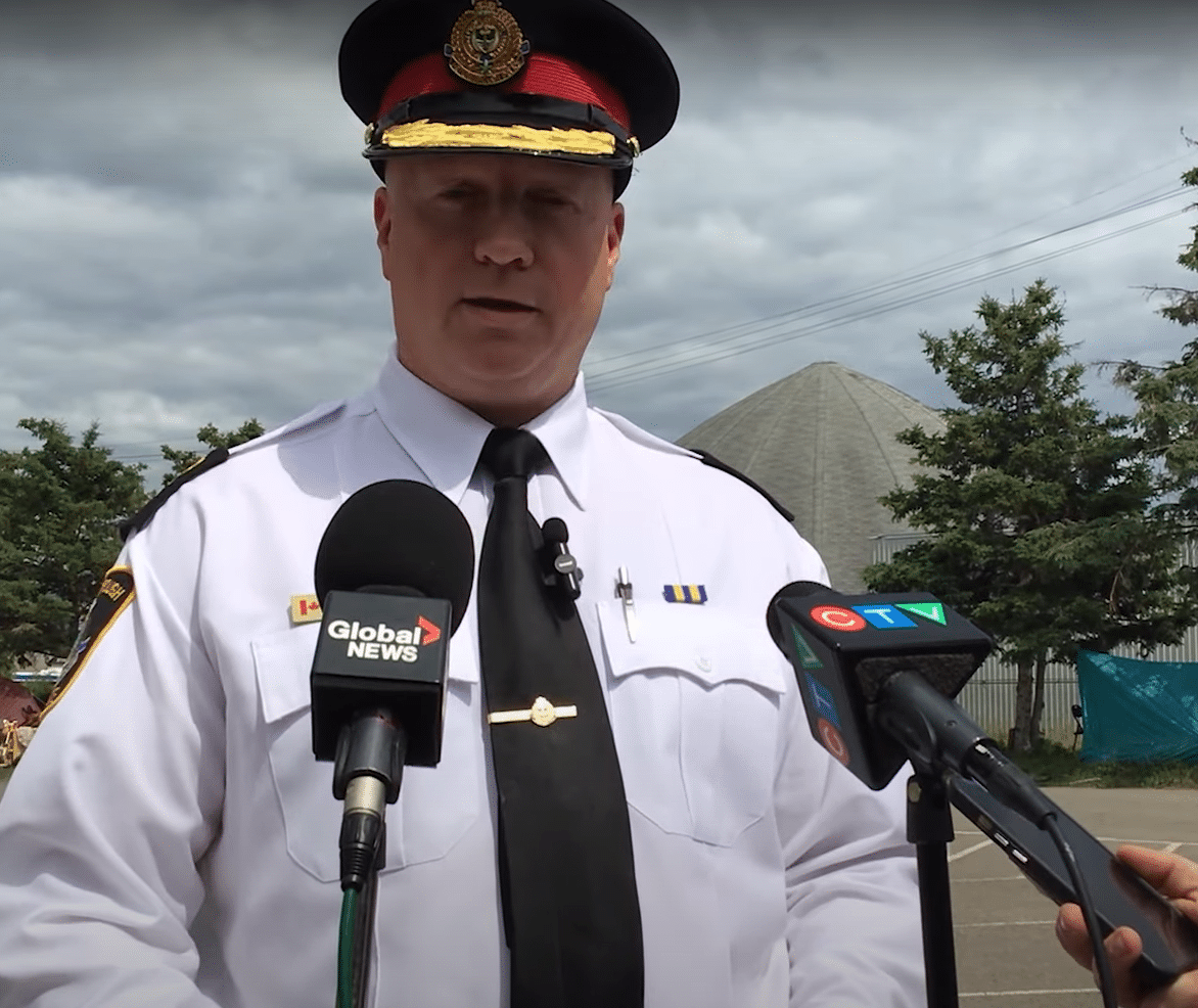 Photo shows Peterborough Police Chief Stuart Betts in uniform standing in front of two microphones at the Wolfe Street tent encampment.
