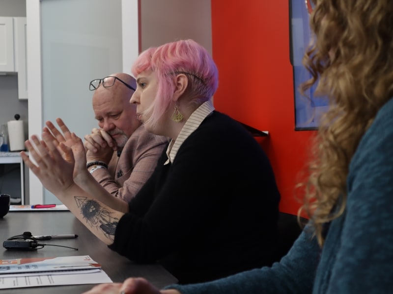 Photo shows three United Way staff members sitting in a row, as one of them (Elisha Rubacha) speaks to the media.