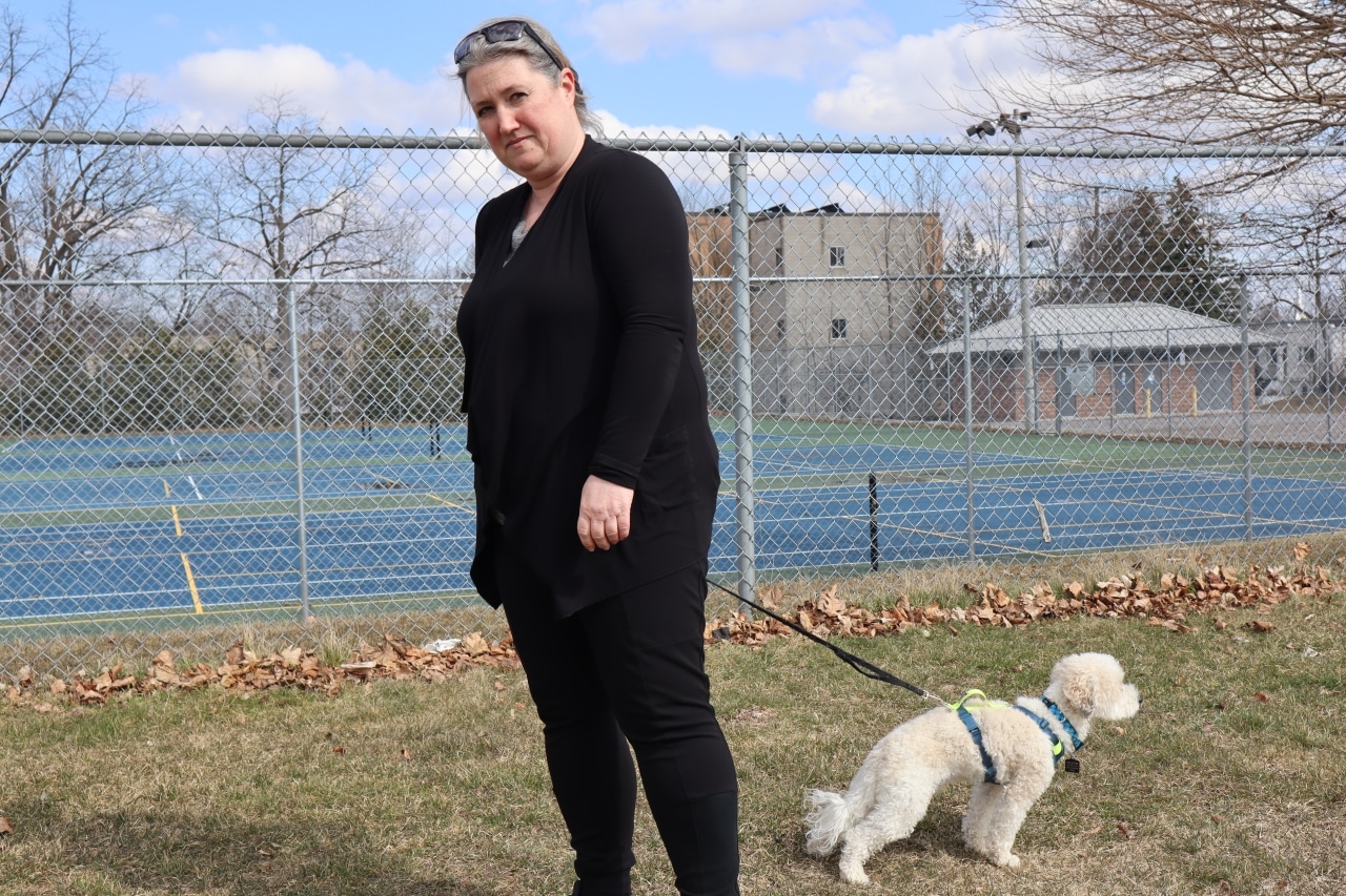Photo shows a woman holding her small dog on a leash in Bonnerworth Park.