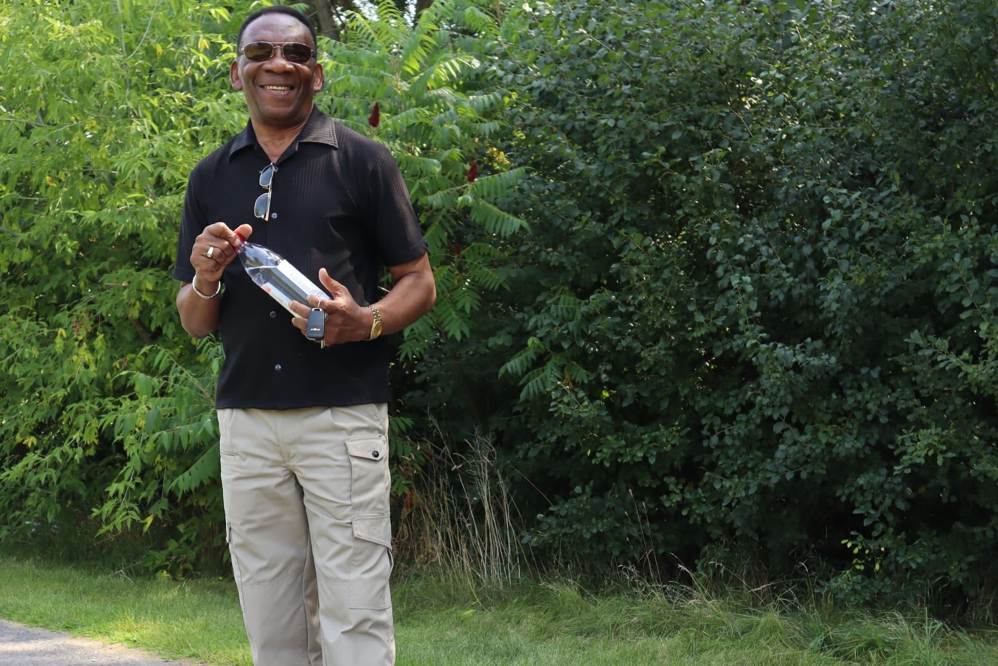 Photo shows Max Rochester smiling while holding a water bottle and car keys. He's standing on the trail with trees behind him.